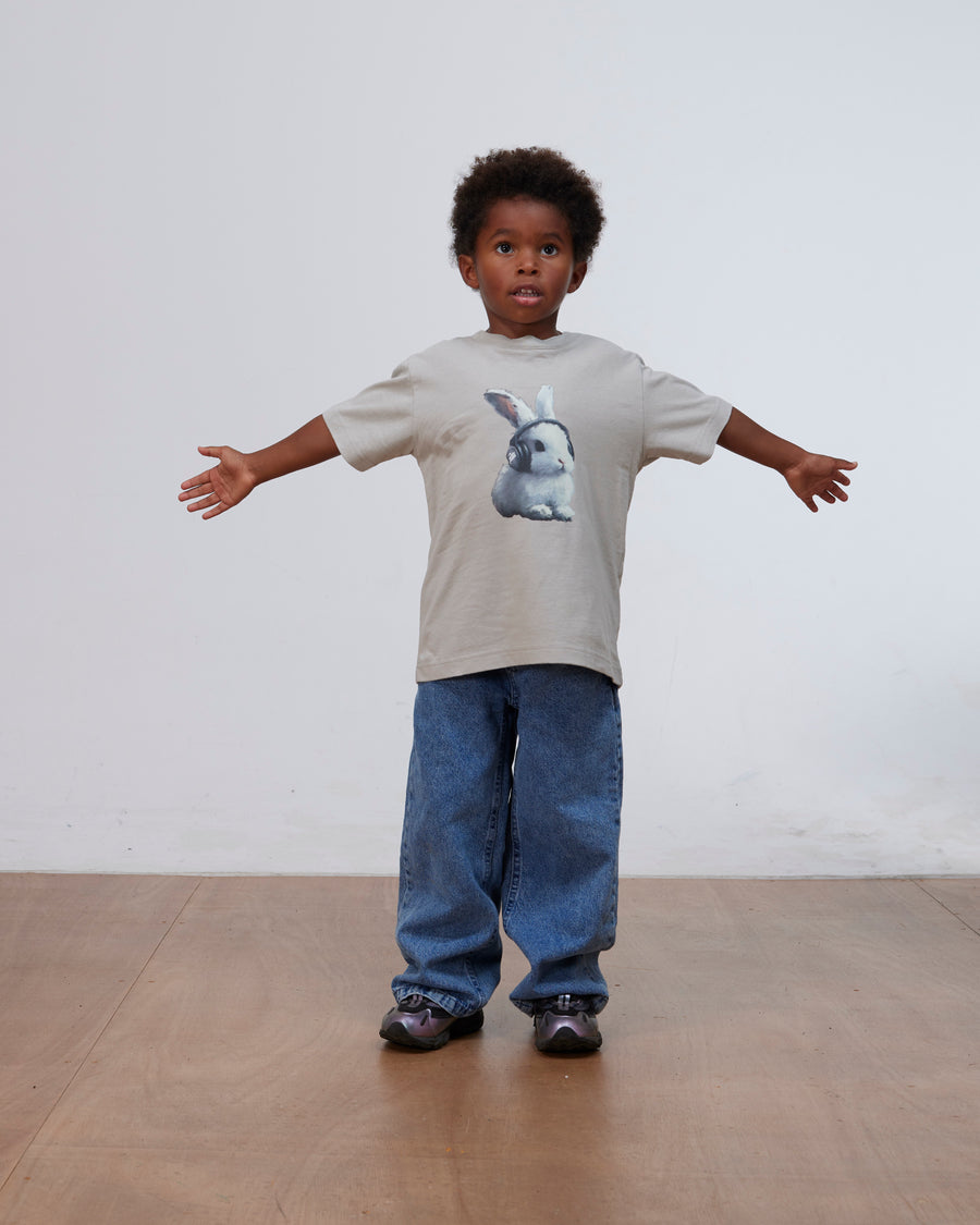 Young boy wearing the flint gray Patta Kids Bunny T-Shirt paired with baggy blue jeans.